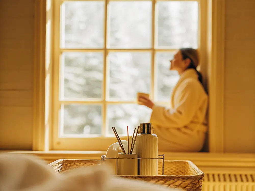 A serene guest by a bright window with a cup of tea, turned to the light